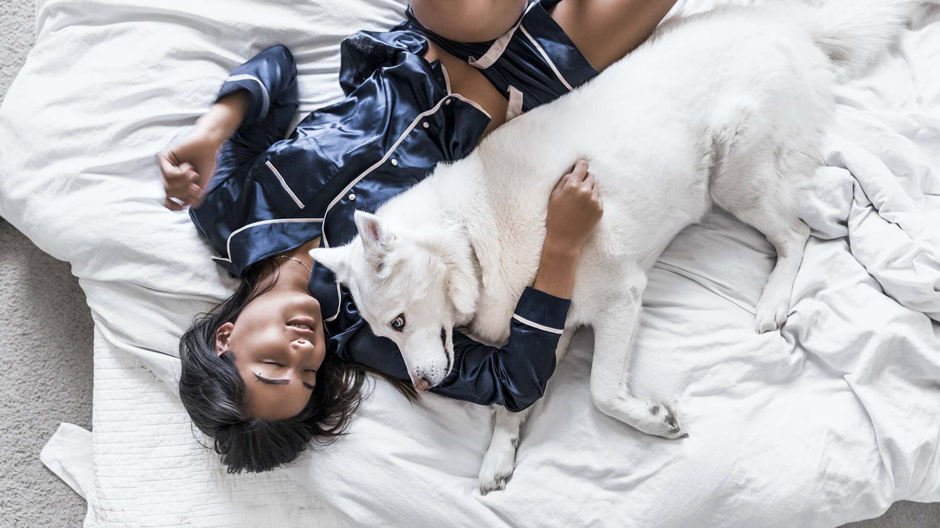a woman laying on a bed with a white dog at The 