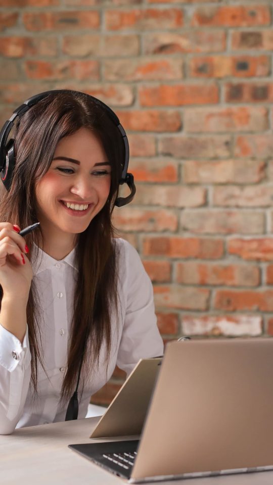 a woman is smiling while working on her laptop at The 