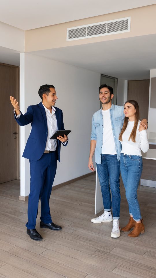 two people standing in an empty house with one pointing at something at The 